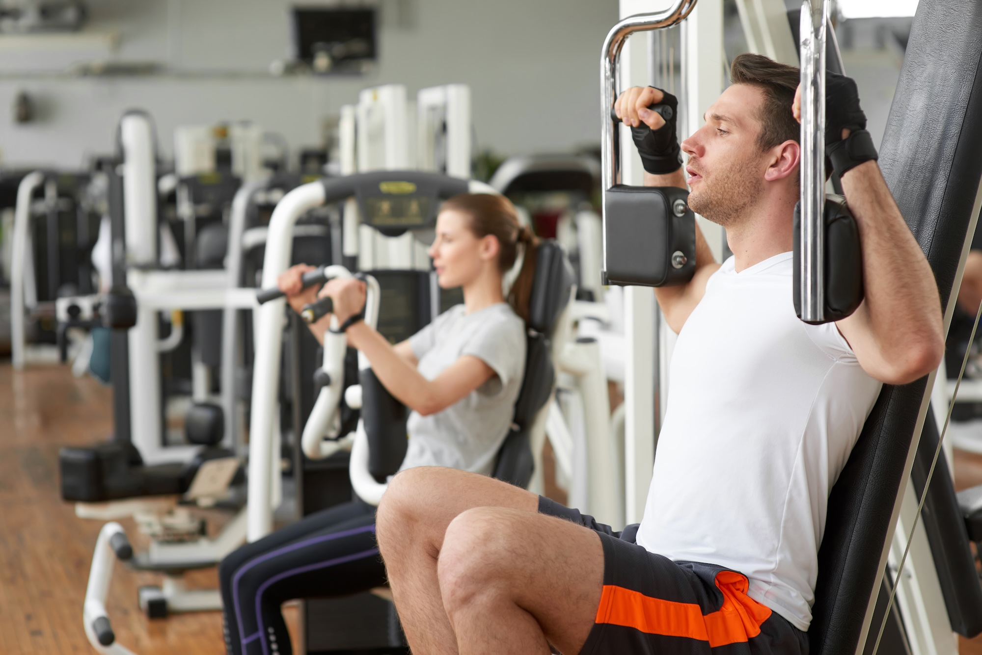 couple works out at a gym fitness center waiting for the cleaning company to wipe down equipment in scottsdale