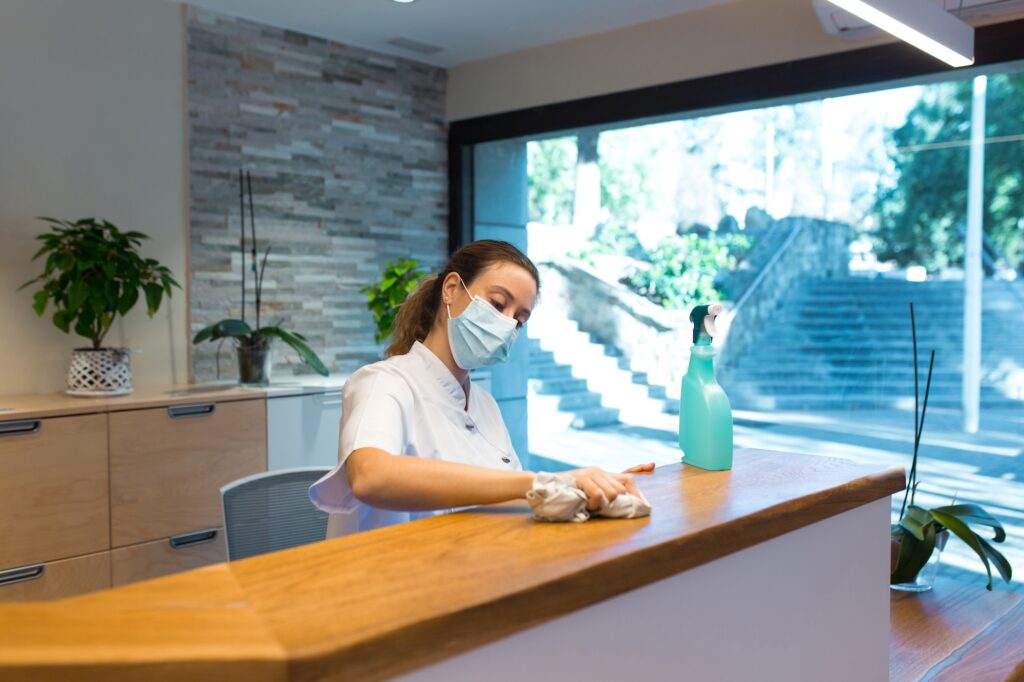 woman from a cleaning company wiping down a desk in an optometrists office in tempe az